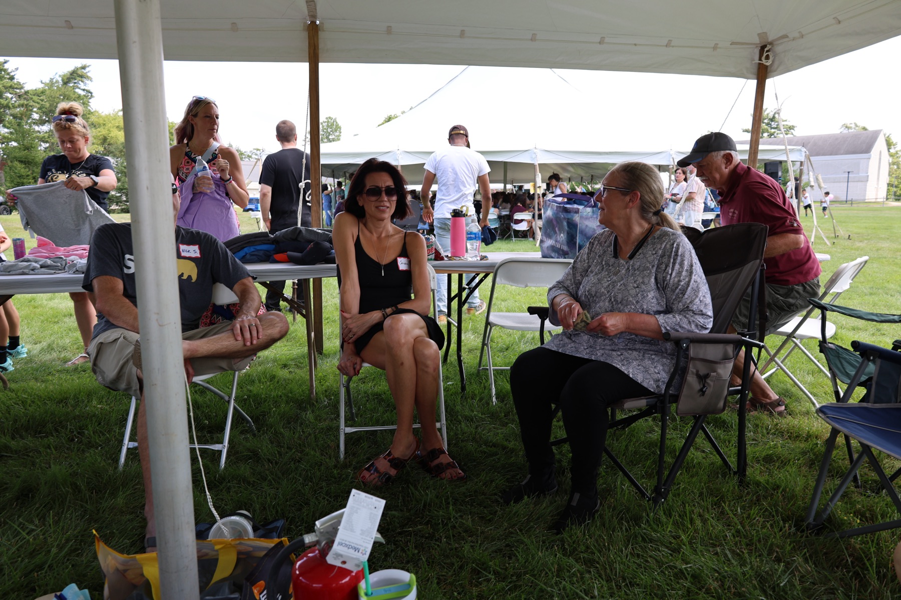 Friends visiting together beneath a tent at Tune Up 2026